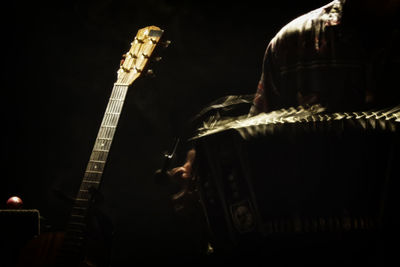 Man playing guitar against black background