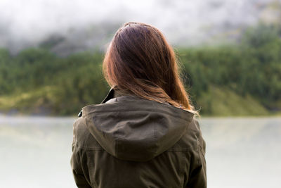 A young beautiful tourist walks along boards through a stormy mountain stream