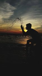 Silhouette man on beach against sky during sunset