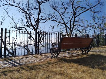 Empty bench on field against sky