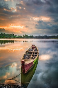 Boat moored in sea against sky during sunset