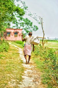 Rear view of woman walking on field