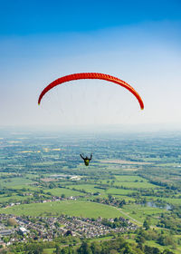 People paragliding over landscape against sky