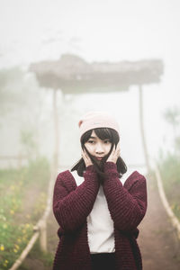 Portrait of young woman standing in park during winter