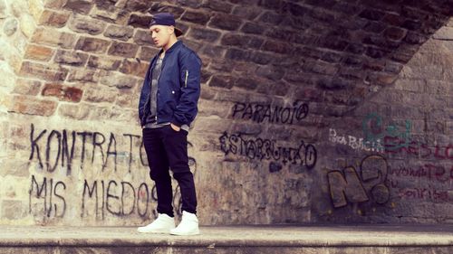 Full length of man standing against graffiti wall