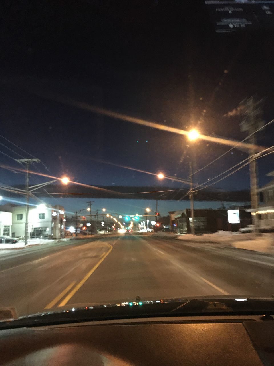 CARS ON ILLUMINATED STREET SEEN THROUGH CAR WINDSHIELD