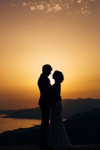 Silhouette couple kissing against sky during sunset