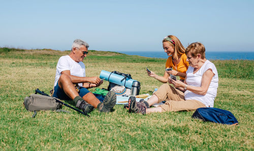 Adult family playing cards sitting on a blanket during an excursion