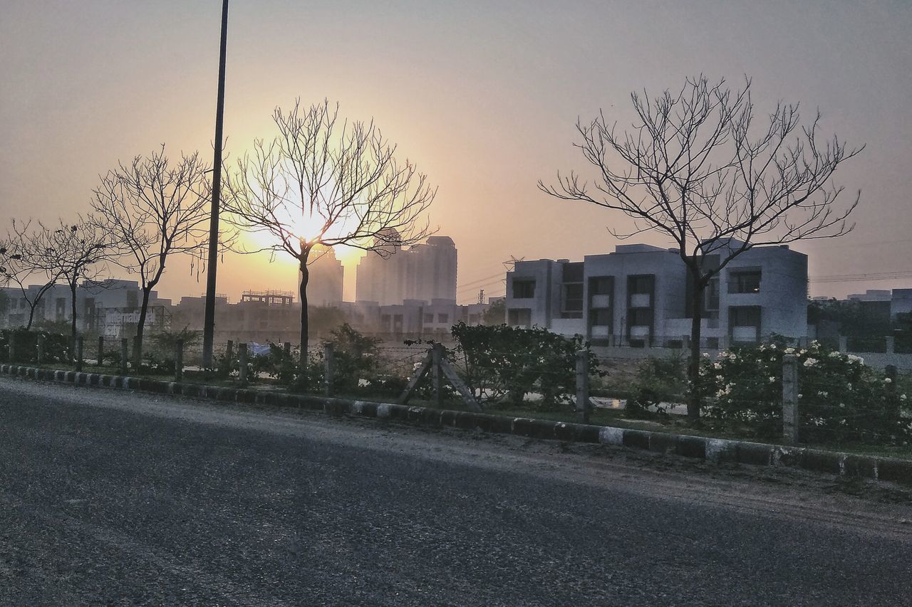 BARE TREES BY BUILDINGS AGAINST SKY