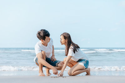 Women sitting on beach against sea