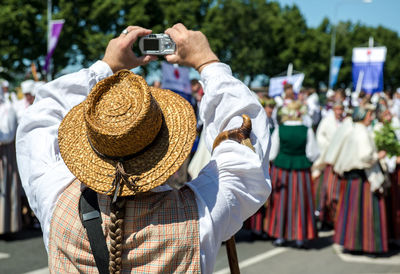 Rear view of woman photographing people standing on street