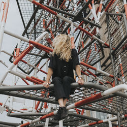 Woman sitting on built structure against sky