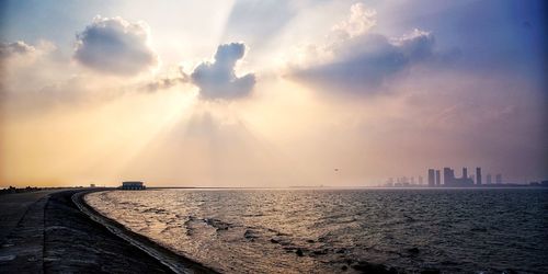 Panoramic view of sea and buildings against sky during sunset