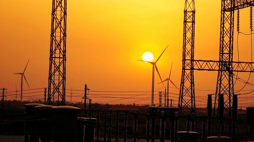 Silhouette electricity pylon against sky during sunset