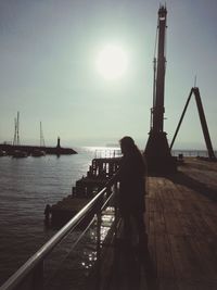 Rear view of silhouette man standing on sea against clear sky