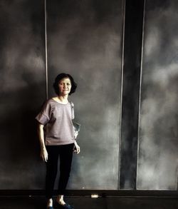 Portrait of woman standing against wall