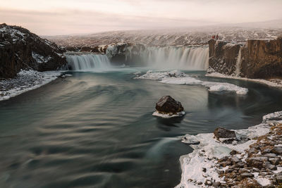 Scenic view of waterfall against sky