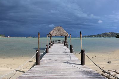 Wooden pier on beach against sky