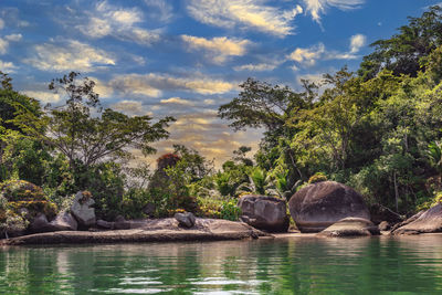 Rocks by lake against sky