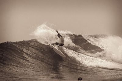 Man surfing in sea against sky