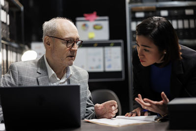 Side view of young woman using laptop at office