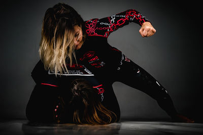 Rear view of woman sitting against black background