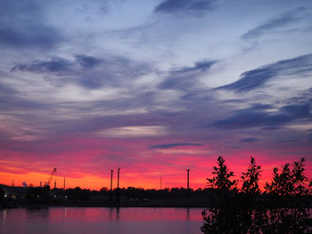 Silhouette of factory against sky during sunset