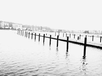 Wooden posts in sea against clear sky