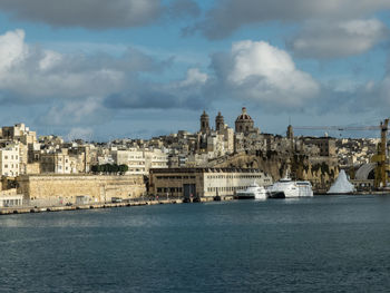 View of cityscape by sea against sky