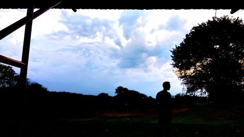 Silhouette of man standing against cloudy sky