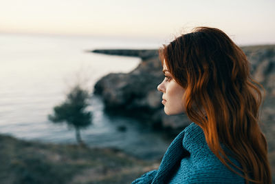 Side view of woman looking at sea against sky