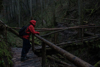 Hiker with backpack standing on footbridge in forest