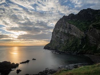 Rock formation on sea against sky during sunset