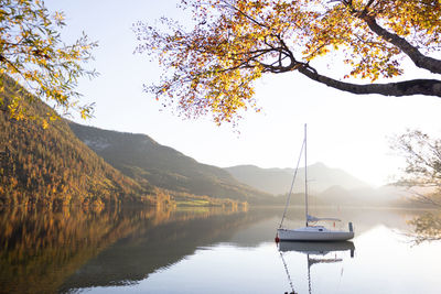 Autumn scene with sailboat and colourful alps on the background