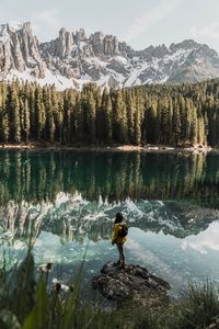 Man standing by lake against mountains during winter