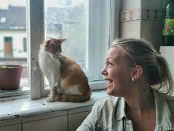 Woman looking at cat on window sill at home