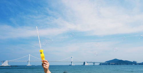 Cropped hand holding bubble wand against gwangandaegyo