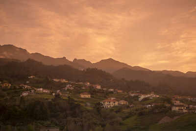 Townscape by mountains against sky during sunset