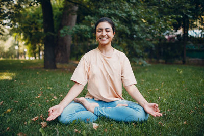 Portrait of smiling young woman sitting on field