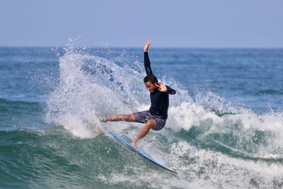 Full length of man surfing in sea against sky