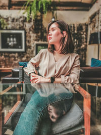 Young woman looking away while sitting on chair