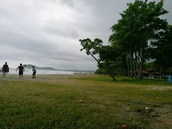 Friends playing soccer on beach against sky
