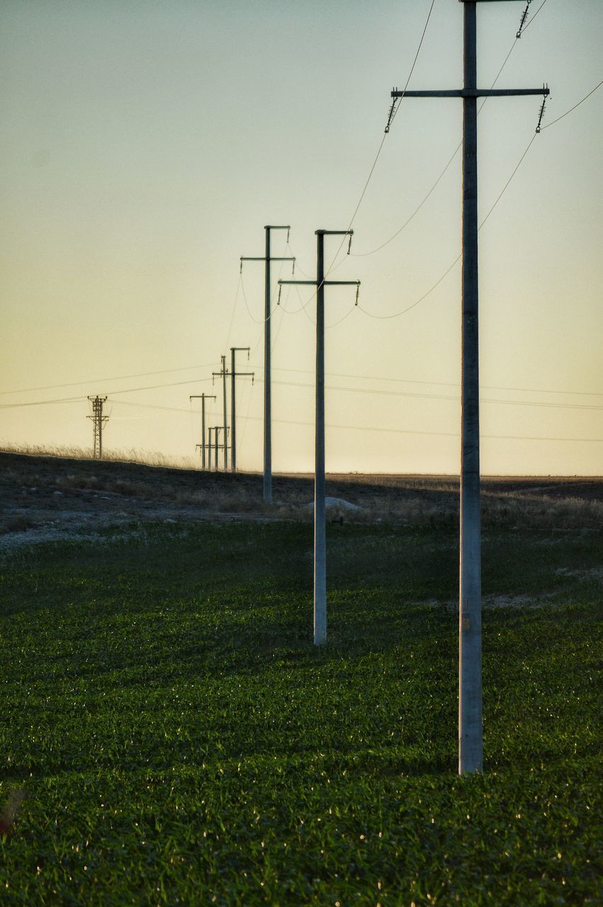 ELECTRICITY PYLON ON FIELD AGAINST SKY