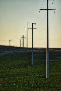 Electricity pylon on field against sky during sunset