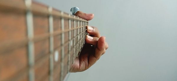 Close-up of hand playing guitar against wall