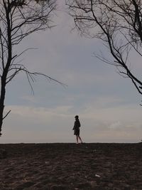 Rear view of woman standing on land against sky