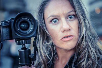 Close-up portrait of shocked woman with camera