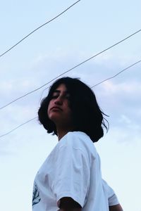 Low angle portrait of woman looking against sky