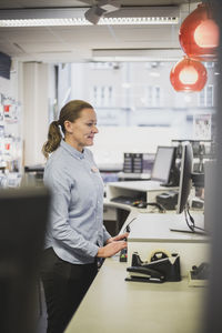 Mature saleswoman working at checkout counter in electronics store