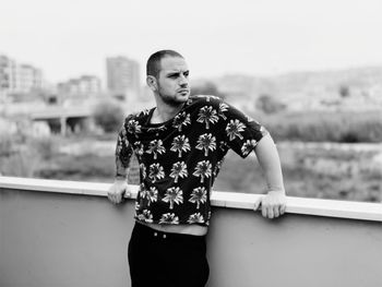 Young man looking away while standing against retaining wall